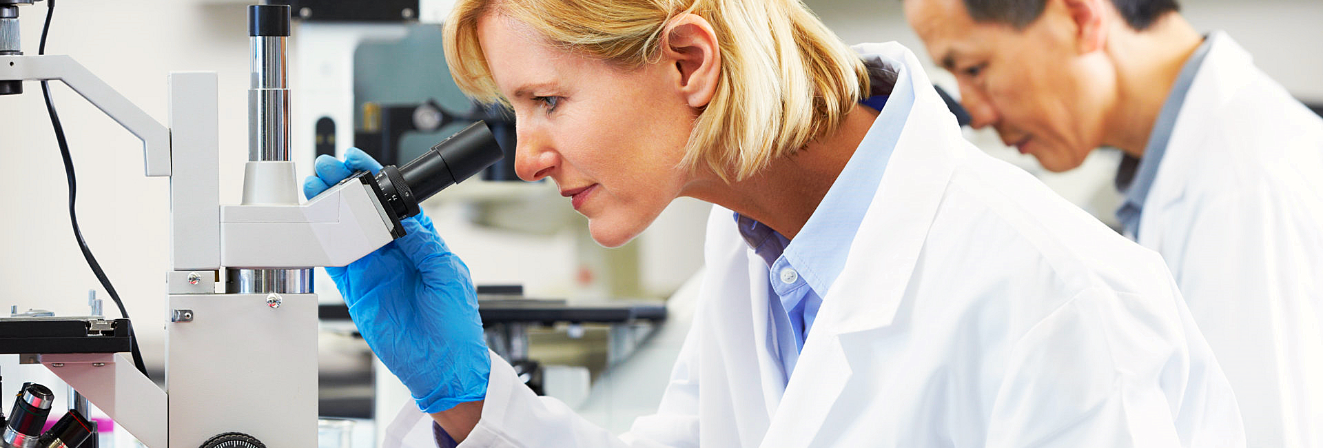 Scientist holding a tablet device while looking at a microscope